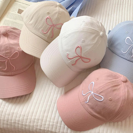 Collection of baseball caps with embroidered bows on a textured surface